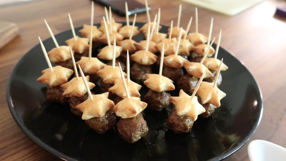 Mini Swedish meatballs on cocktail picks, drizzled with creamy sauce and garnished with dill