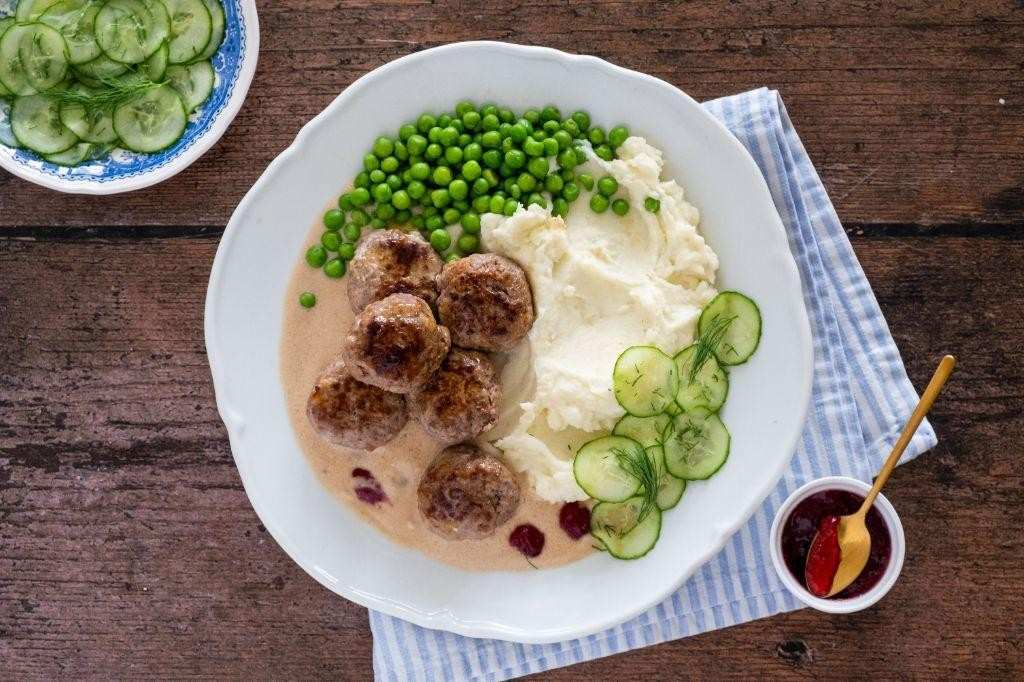 Swedish meatballs plated alongside crisp, translucent Swedish pickled cucumber slices