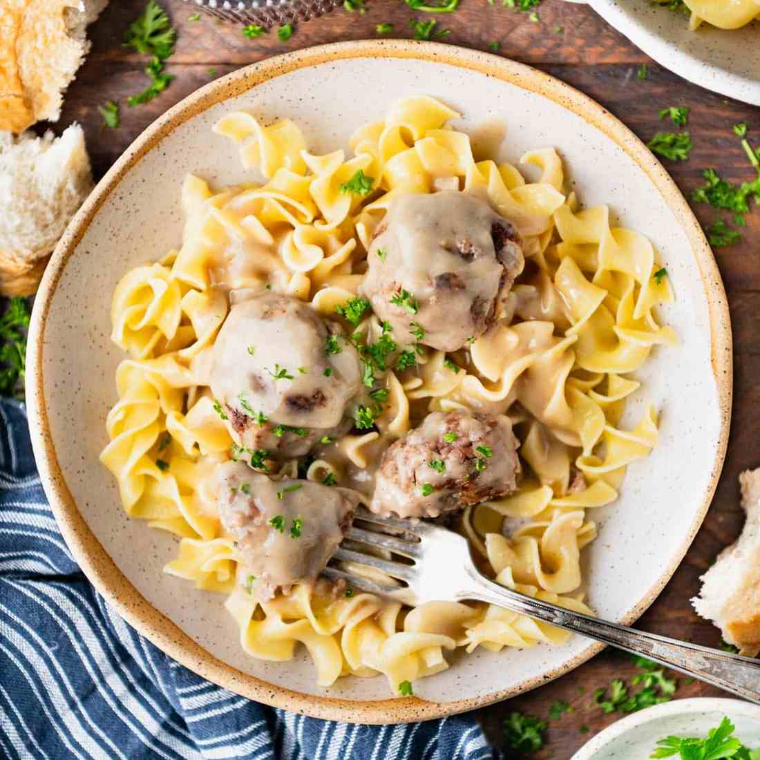The ultimate skillet of golden Swedish meatballs swimming in bubbling velvety cream sauce with fresh herbs