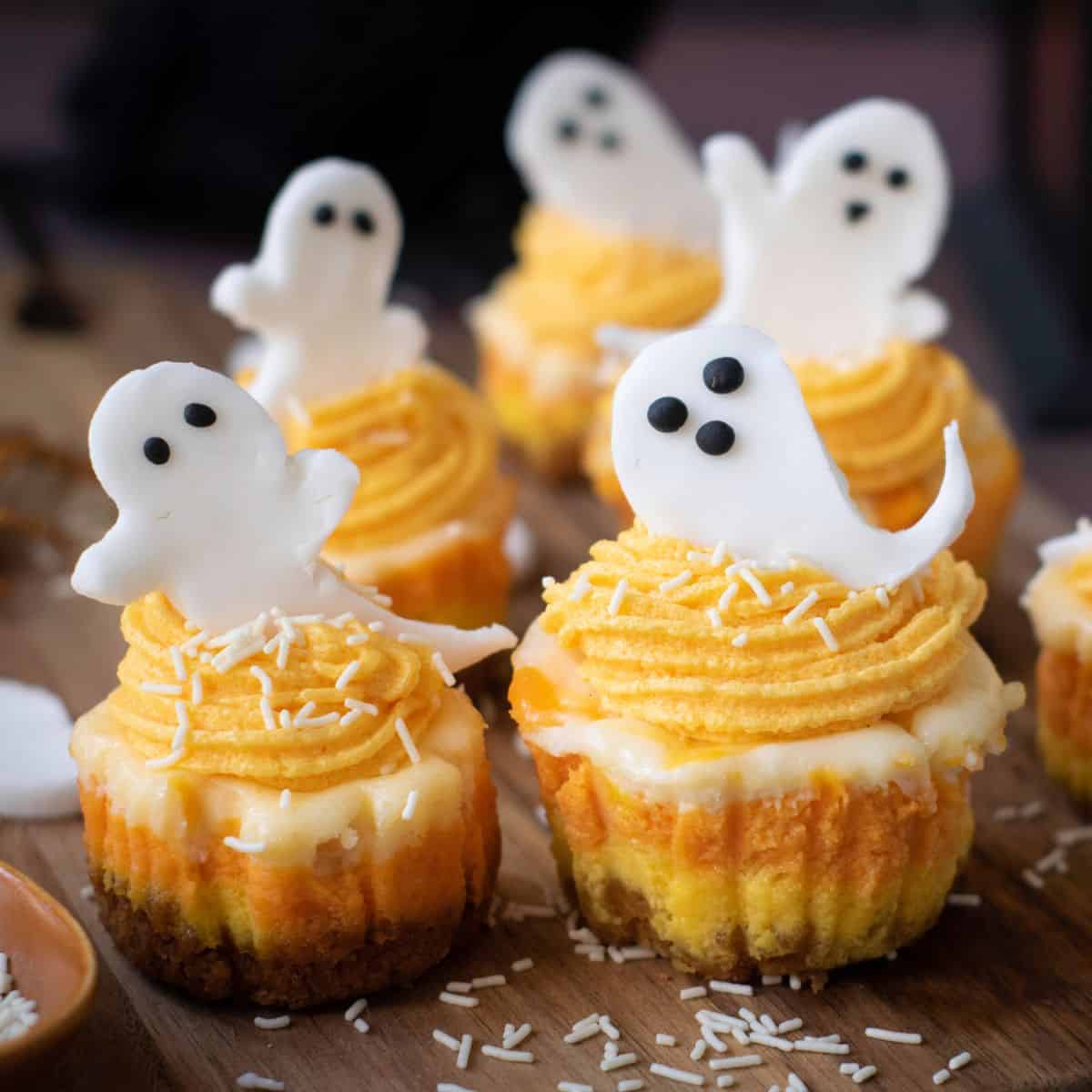 Mini cheesecakes in a cup with a layer of orange, yellow, and white cream in the center.