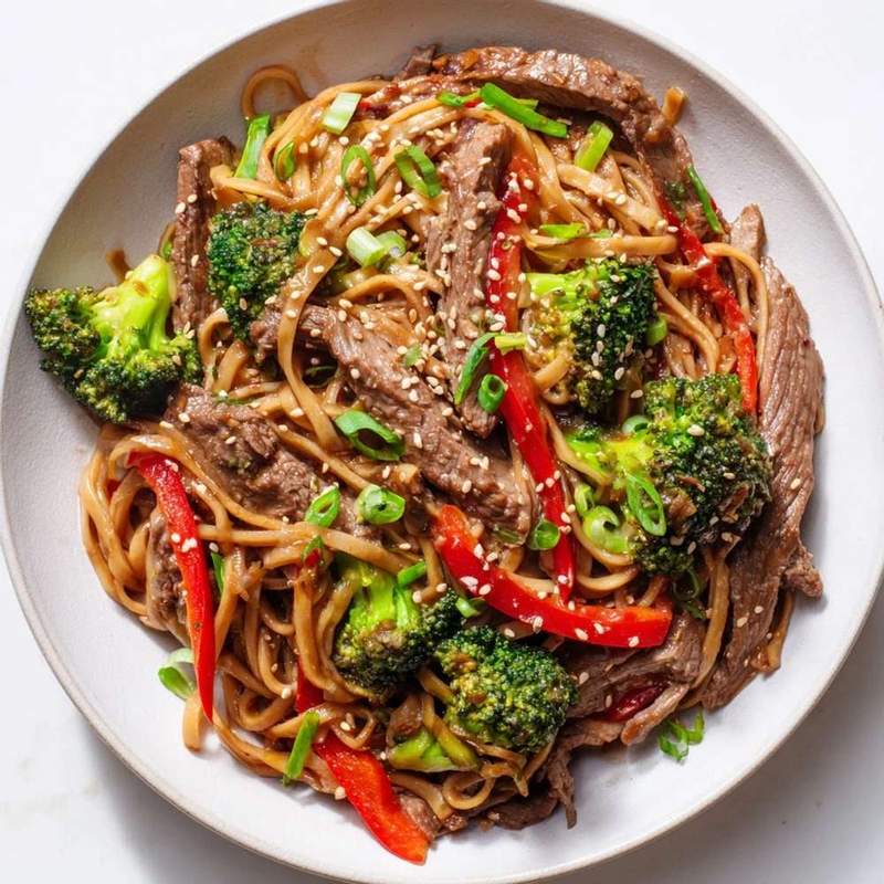 Beef and broccoli noodle bowl with bell peppers, tender beef, crisp broccoli, glossy noodles in savory sauce