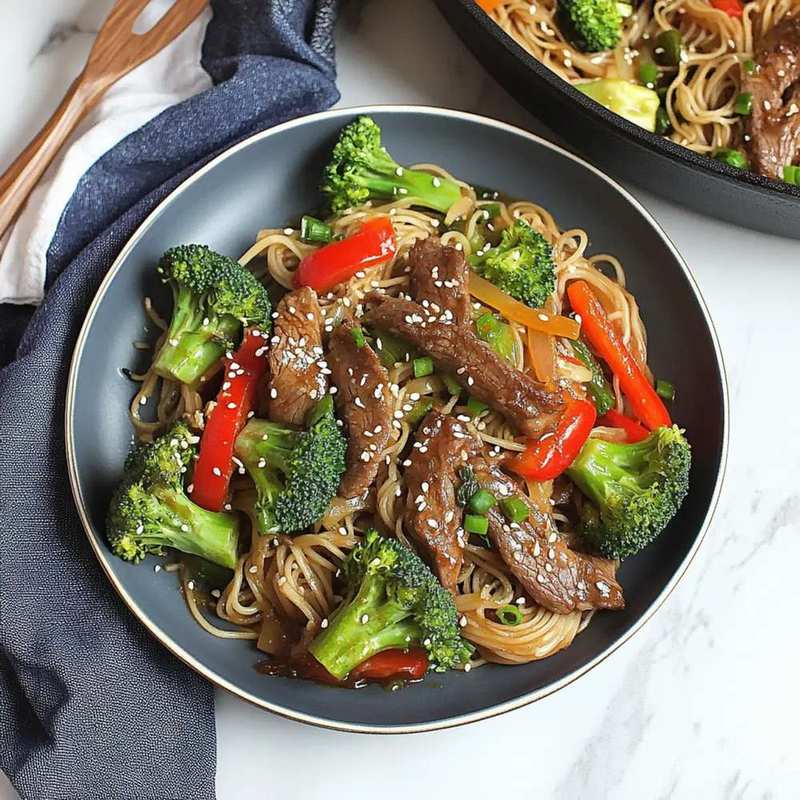 Colorful beef and broccoli noodle bowl with bell peppers, tender beef, crisp broccoli, and glossy sauce