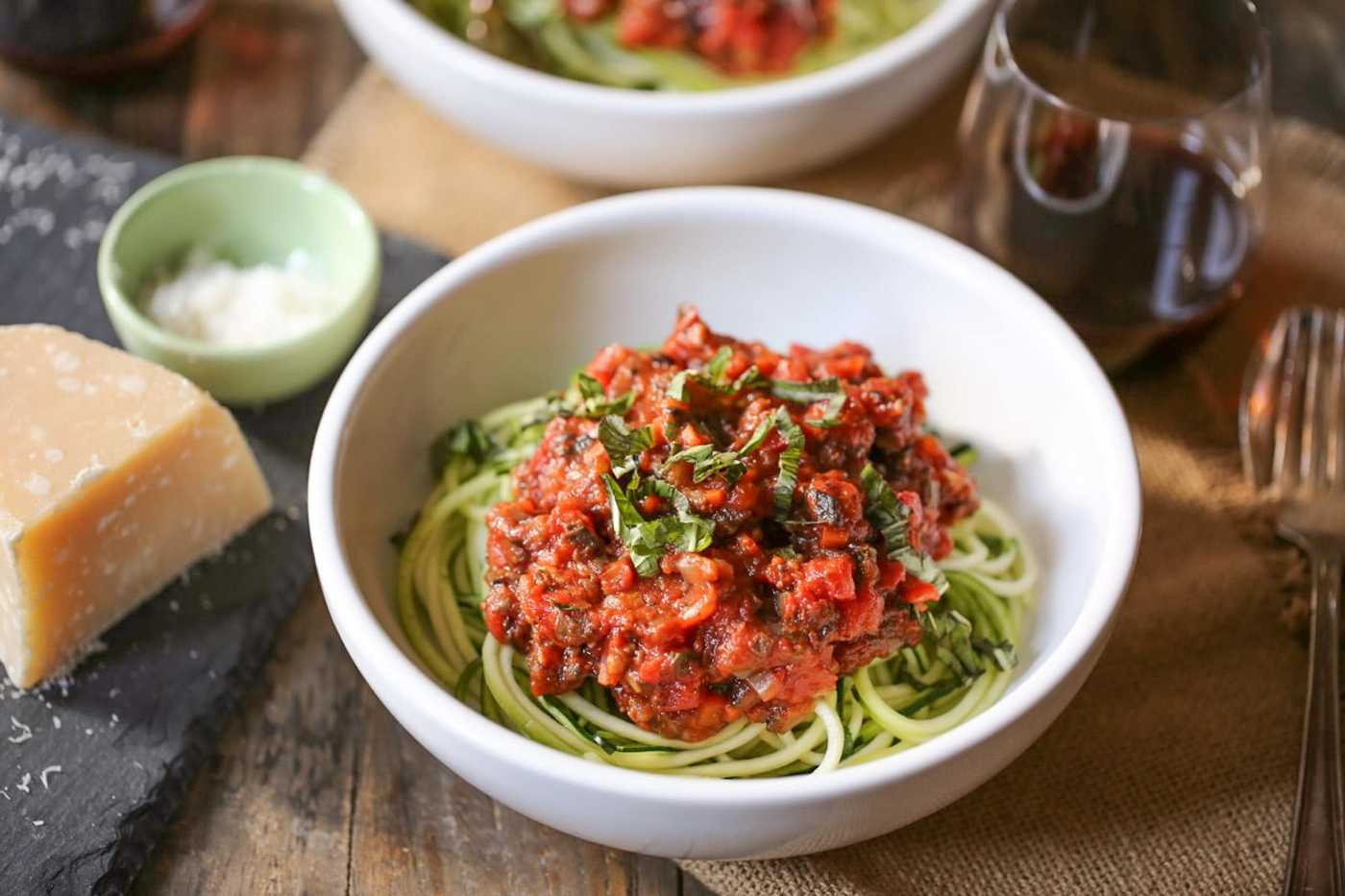 Vegan zucchini noodle bolognese tossed in a vibrant tomato sauce, fresh herbs.