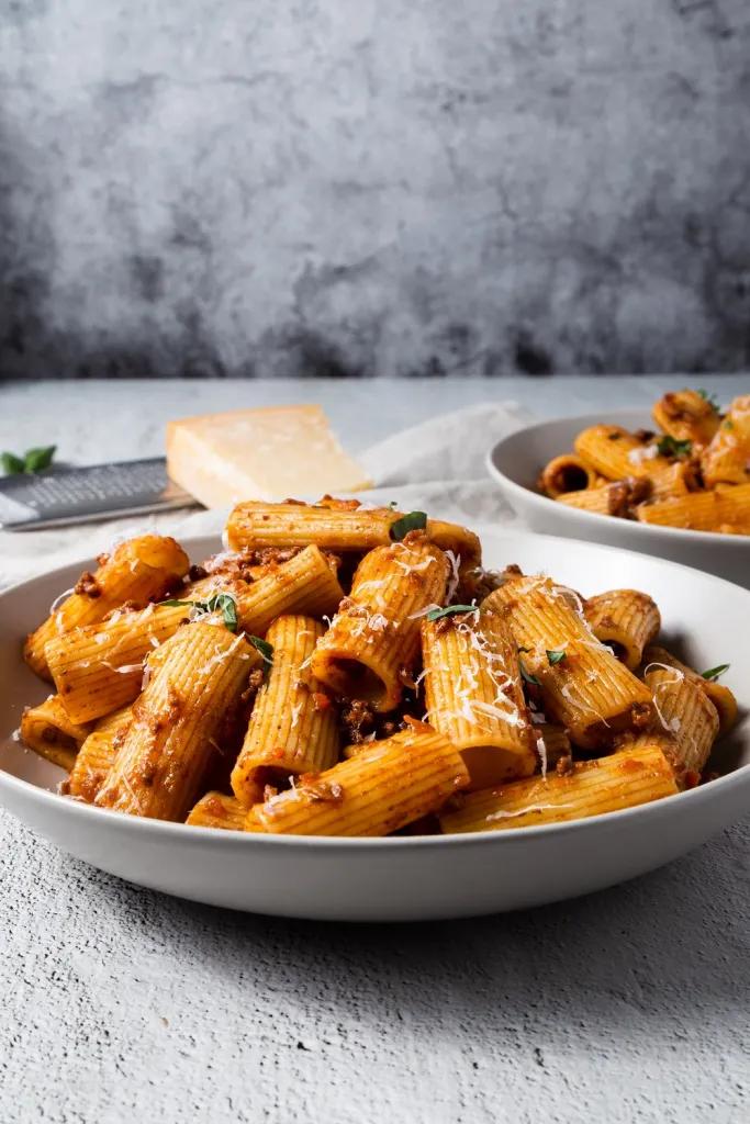 Rigatoni bolognese showcases beef bolognese, parmesan, fresh basil, rich tomato sauce, pasta in hearty bake