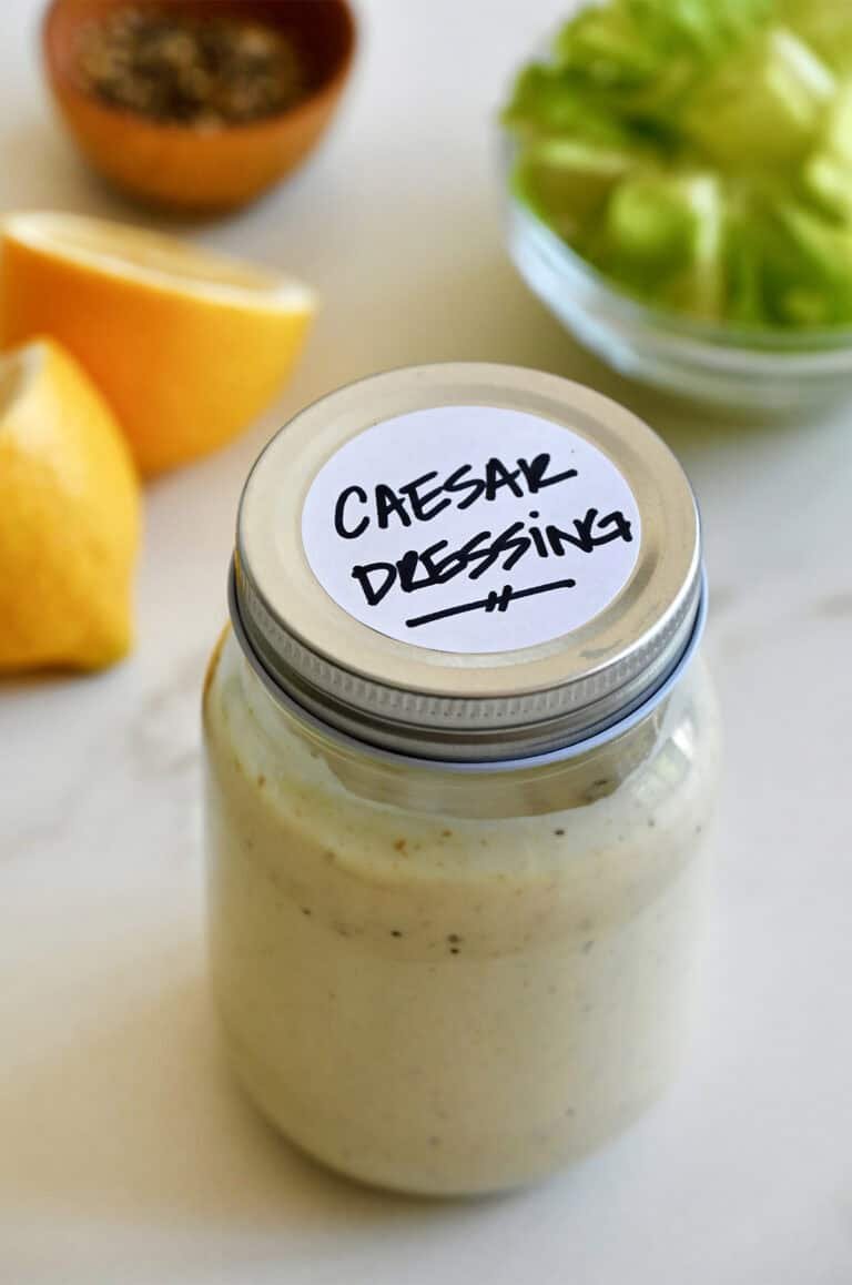 Glass jar of homemade caesar dressing with fresh egg yolk lemon garlic anchovy paste and parmesan