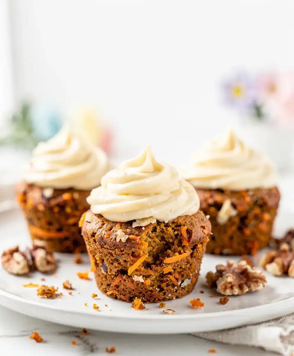 Moist carrot cake cupcake topped with bright tangy cream cheese frosting and toasted walnuts