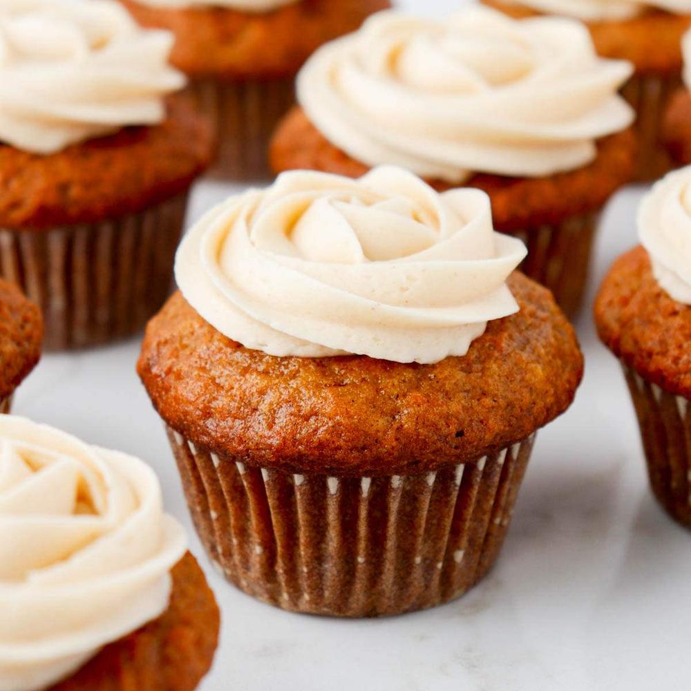 Classic carrot cake cupcakes topped with butter‑cream carrot decorations and cream cheese frosting