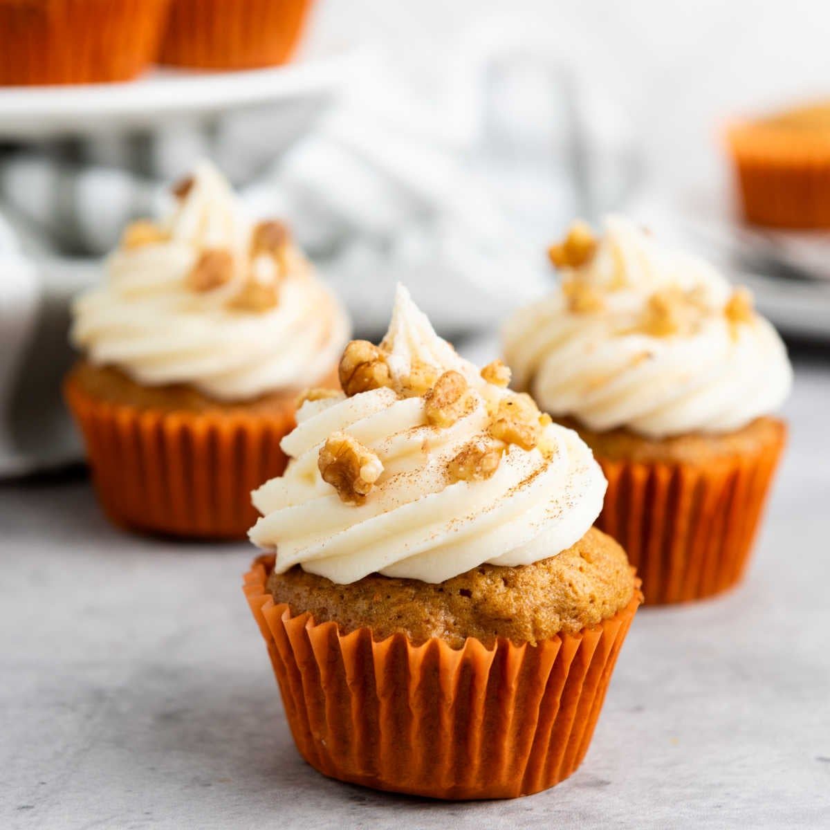 Classic carrot cake cupcake with moist spiced carrot crumb, creamy frosting, and a sprinkle of chopped pecans