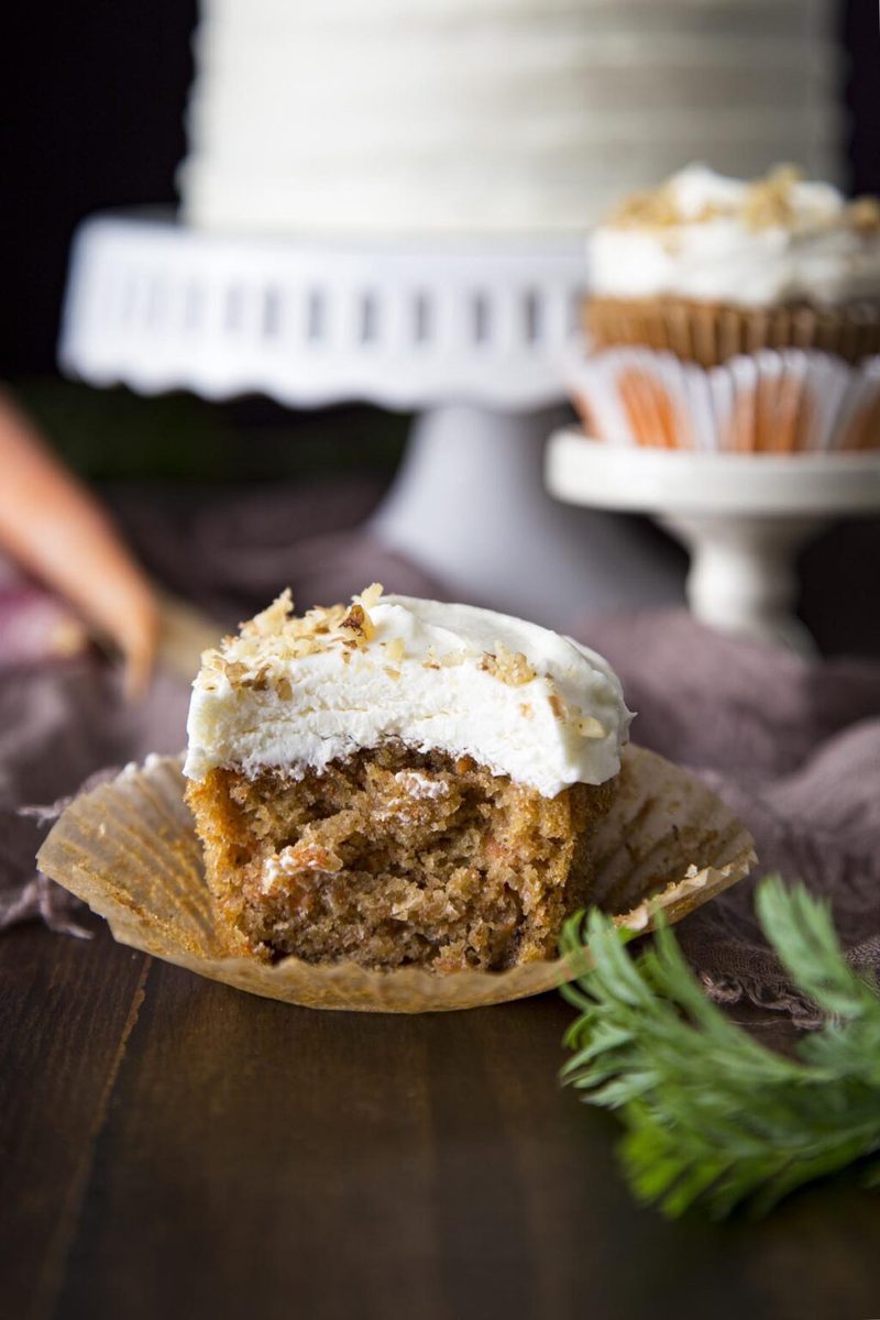 Moist carrot cupcake with a bite taken, revealing fluffy interior and creamy frosting