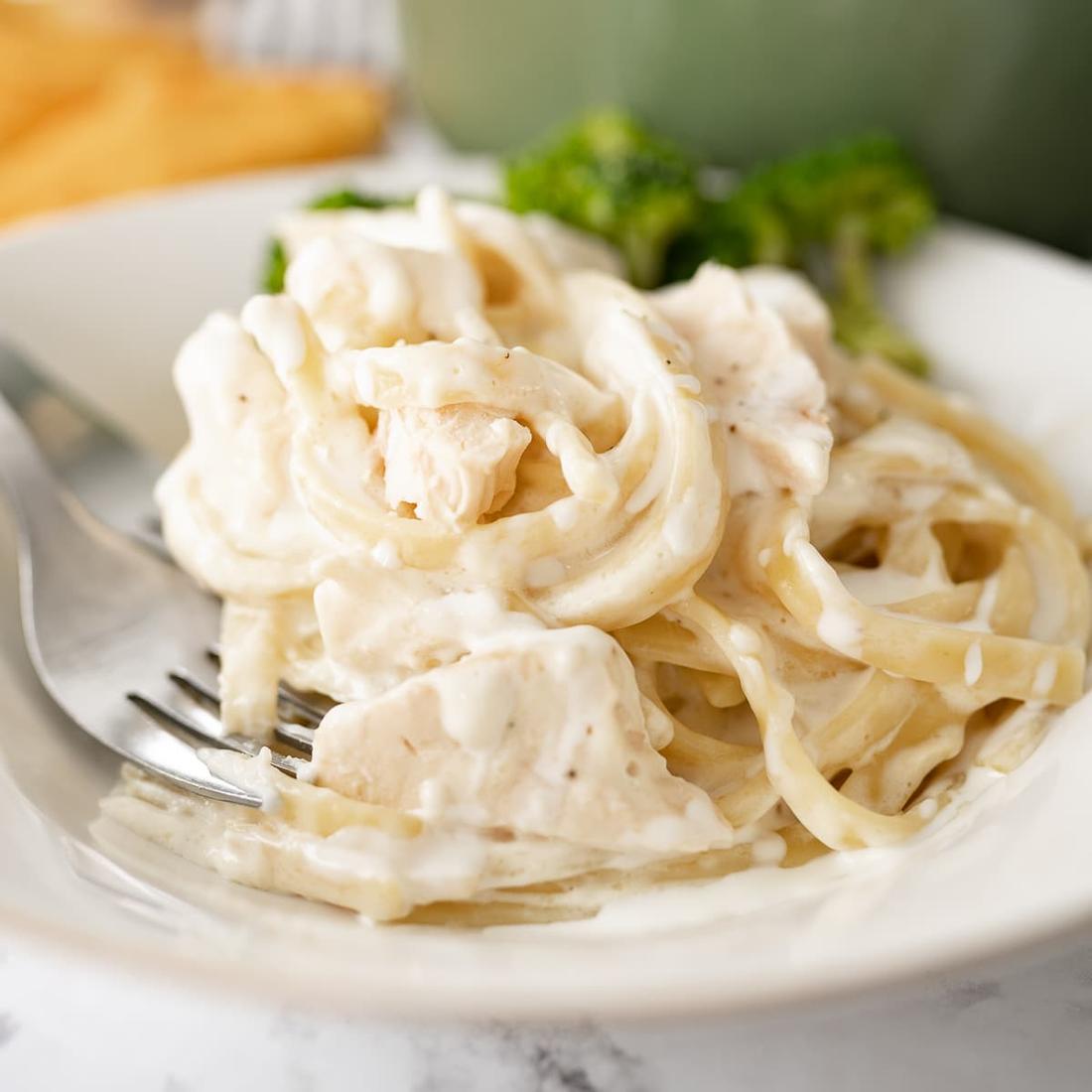 Plated classic fettuccine chicken alfredo featuring tender chicken slices over silky parmesan cream sauce.
