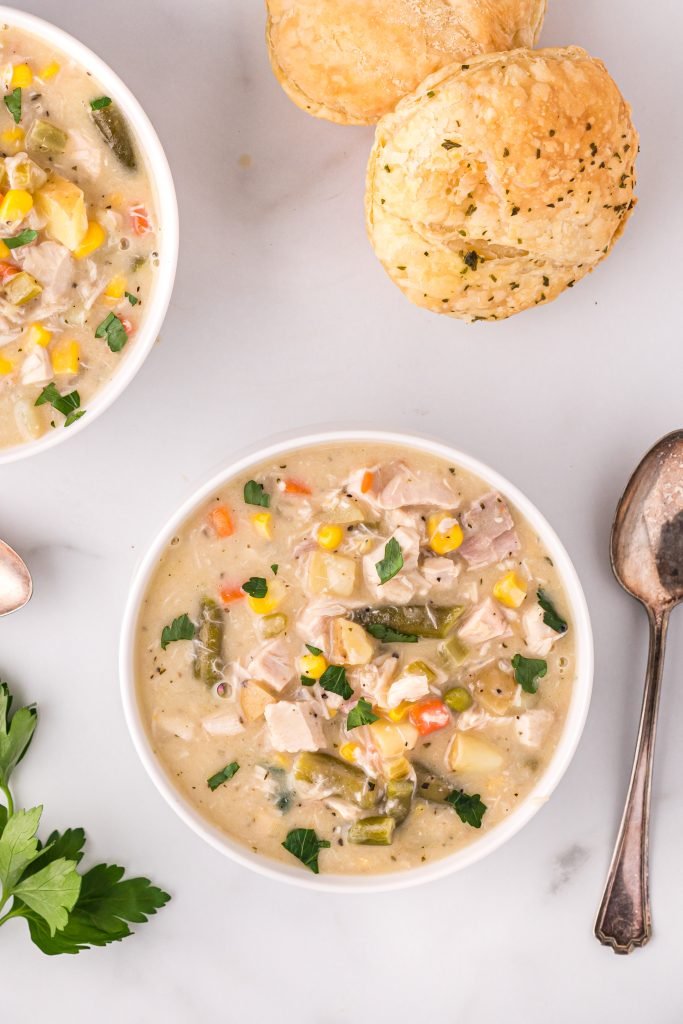 Classic creamy chicken pot pie soup with tender chicken, carrots, peas, potatoes, and a buttery biscuit topping