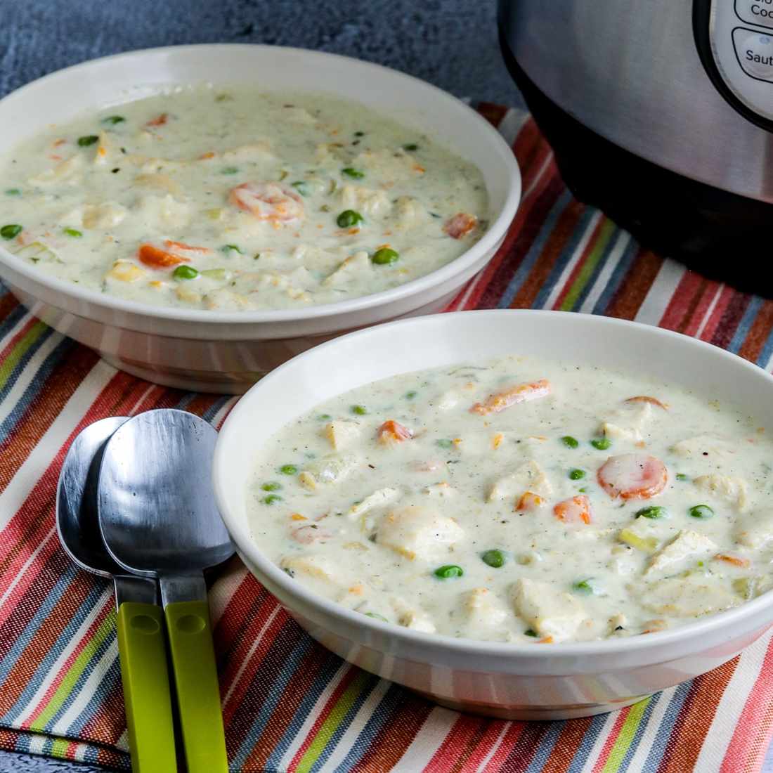 Instant Pot chicken pot pie soup with creamy broth, tender chicken, carrots, peas, potatoes, and a buttery biscuit topping