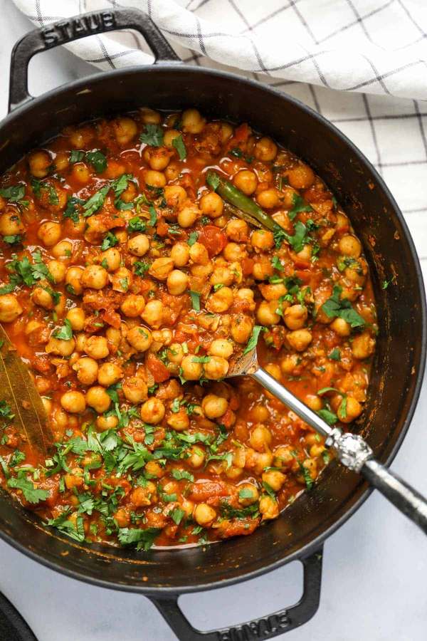 Chunky chickpea curry simmered in a spicy tomato sauce, garnished with fresh coriander, served alongside fluffy rice.