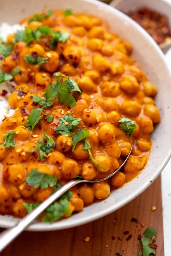 Hearty Thai red chickpea curry with tender squash in velvety coconut sauce garnished with aromatic cilantro.