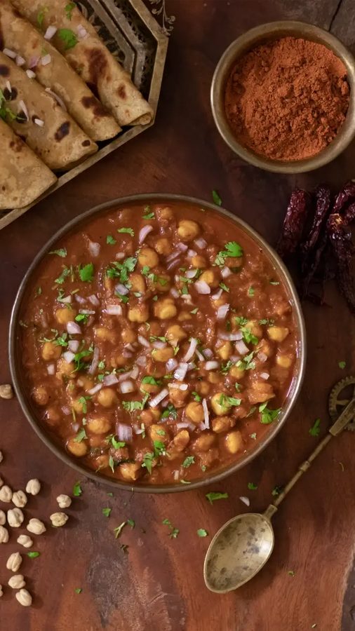 Tangy classic chana masala stewed with chickpeas, spiced amchur curry sauce, cilantro, and hot rice.