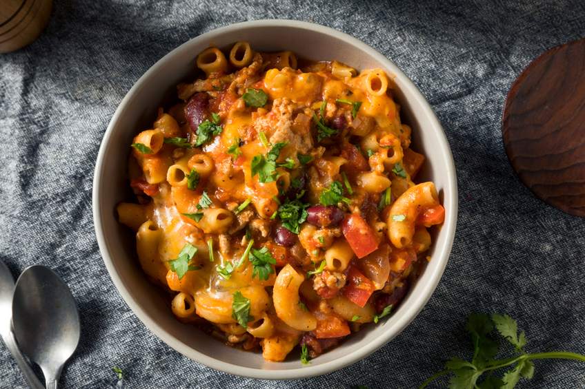 Hearty bowl of cheesy chili mac with beans, beef, melted cheese, sour cream, jalapenos