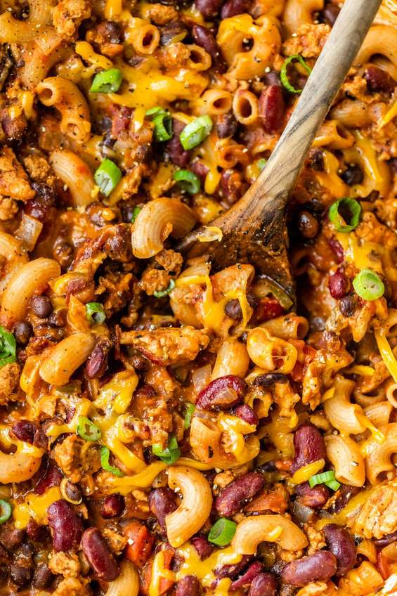 Baked cheesy chili mac bowl with beef, beans, melted cheese, sour cream, jalapenos, golden crust