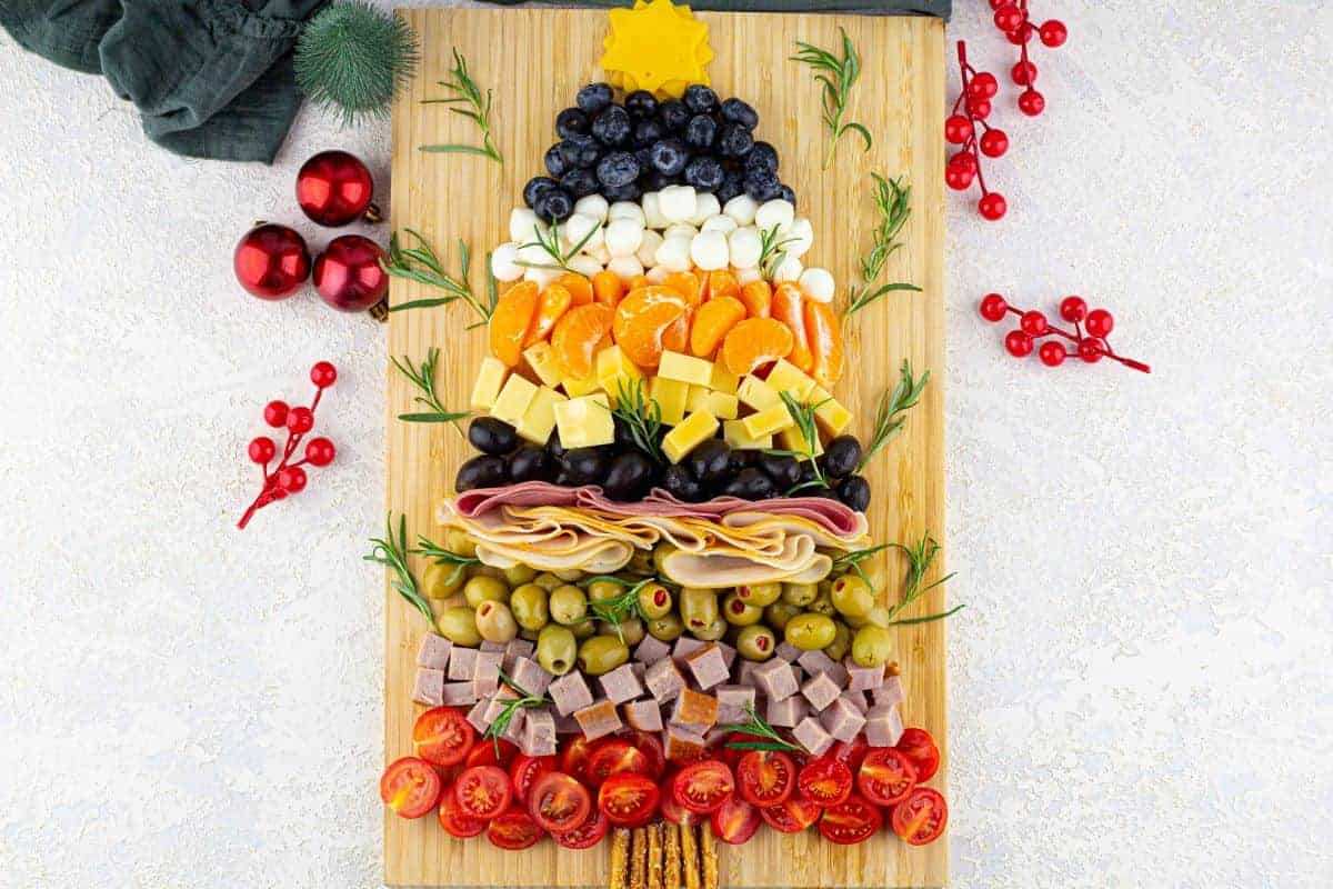 Charcuterie board shaped like a Christmas tree with cured meats, cheeses, nuts, and berries