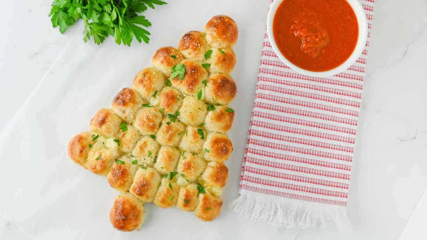 Green‑colored pull‑apart bread shaped like a tree, served with warm marinara dipping sauce