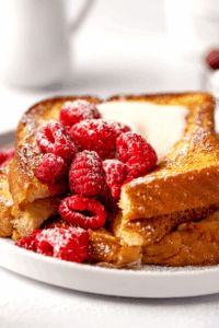 Thick brioche slices soaked in custard, topped with plump raspberries and powdered sugar