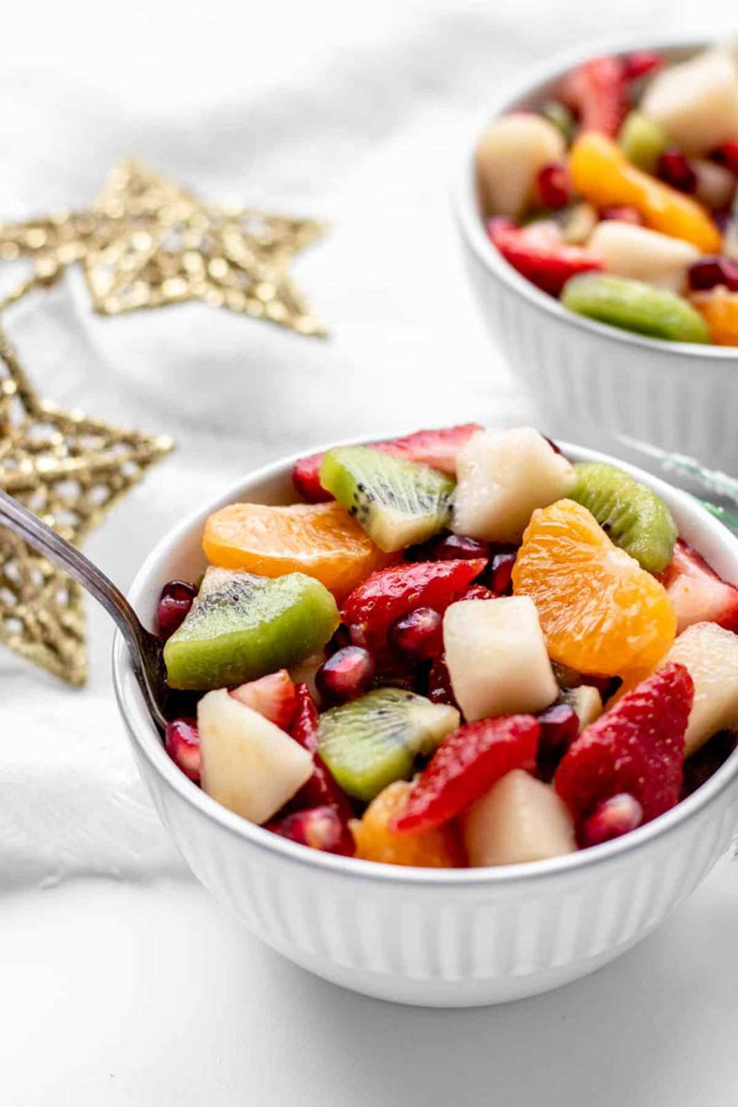 Bright fruit salad bowl with sliced kiwi, ruby pomegranate seeds, and mint leaves