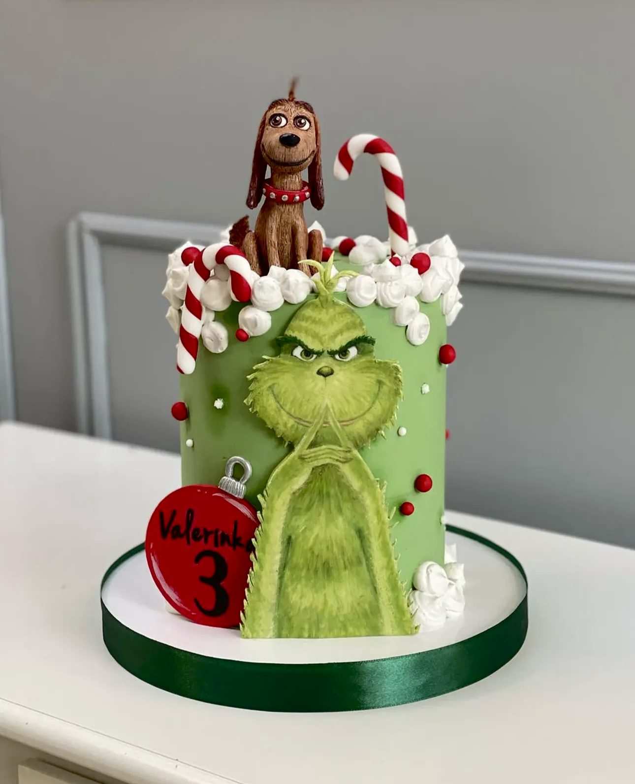 Green chocolate cake shaped like the Grinch with a tiny dog Max figurine on top