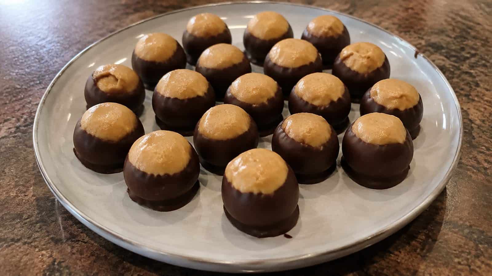Round peanut butter cookies coated in milk chocolate with a peanut butter center exposed on top.