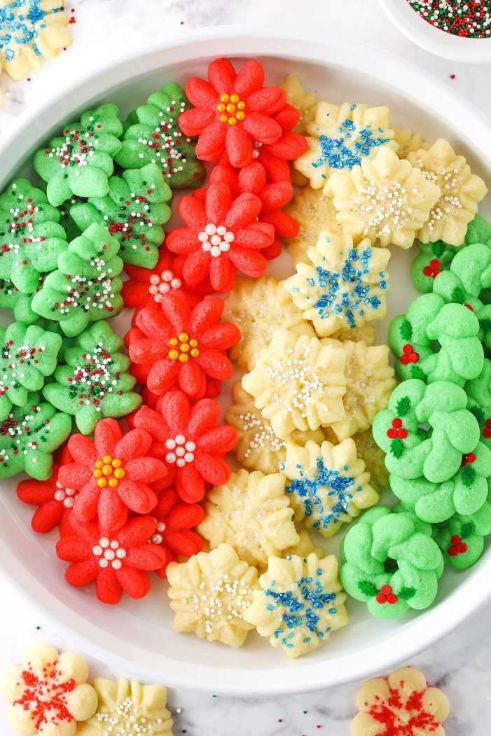 Assorted shapes of butter spritz cookies including stars and trees on a festive platter.