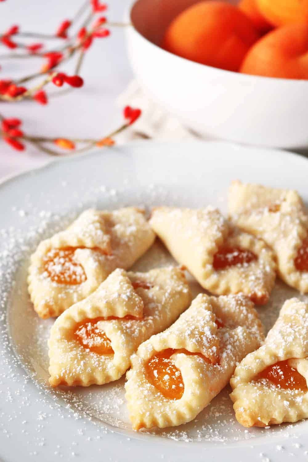 Crescent-shaped shortbread cookies with a slice of apricot jam in the center, dusted with powdered sugar.