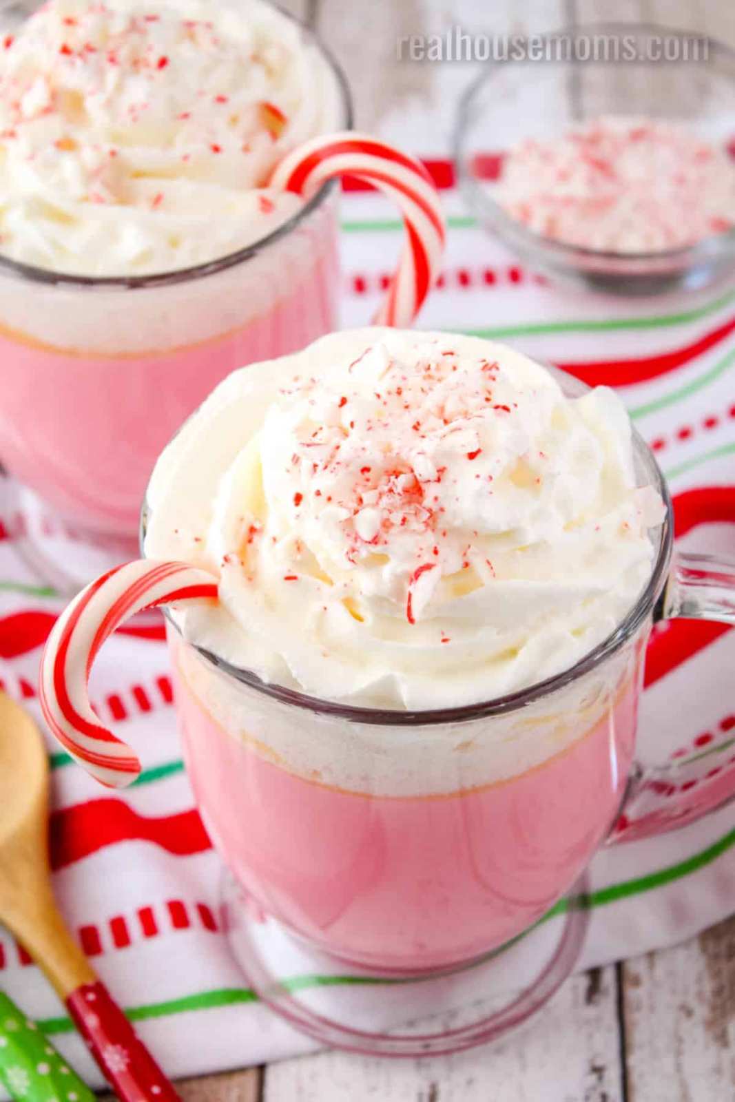 Steaming white chocolate drink topped with whipped cream, peppermint sticks, and a dusting of cocoa