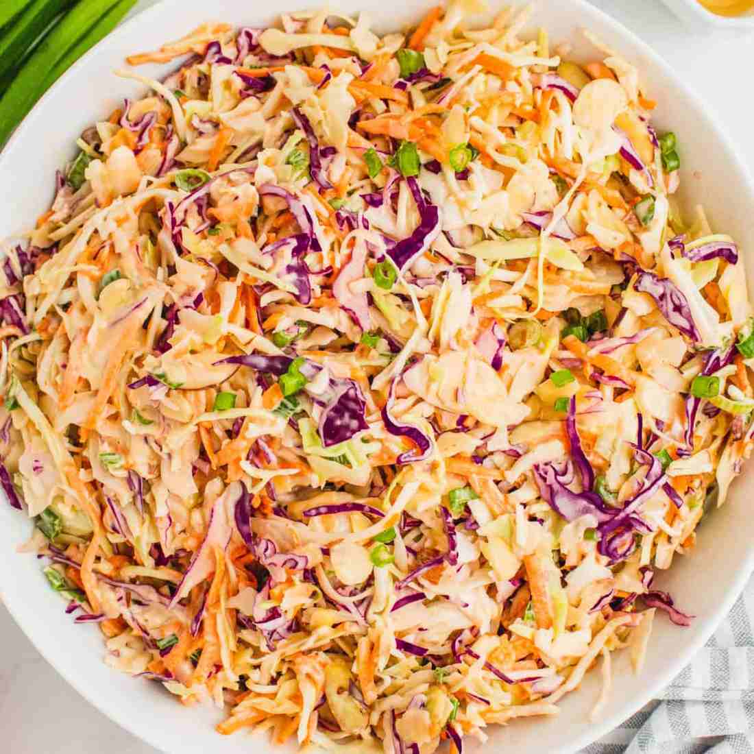 Spicy sriracha coleslaw with crisp cabbage, carrots, and a fiery creamy dressing, garnished with cilantro