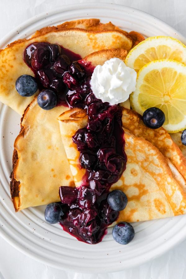 Thin golden crepes filled with tangy lemon and fresh blueberries, topped with powdered sugar