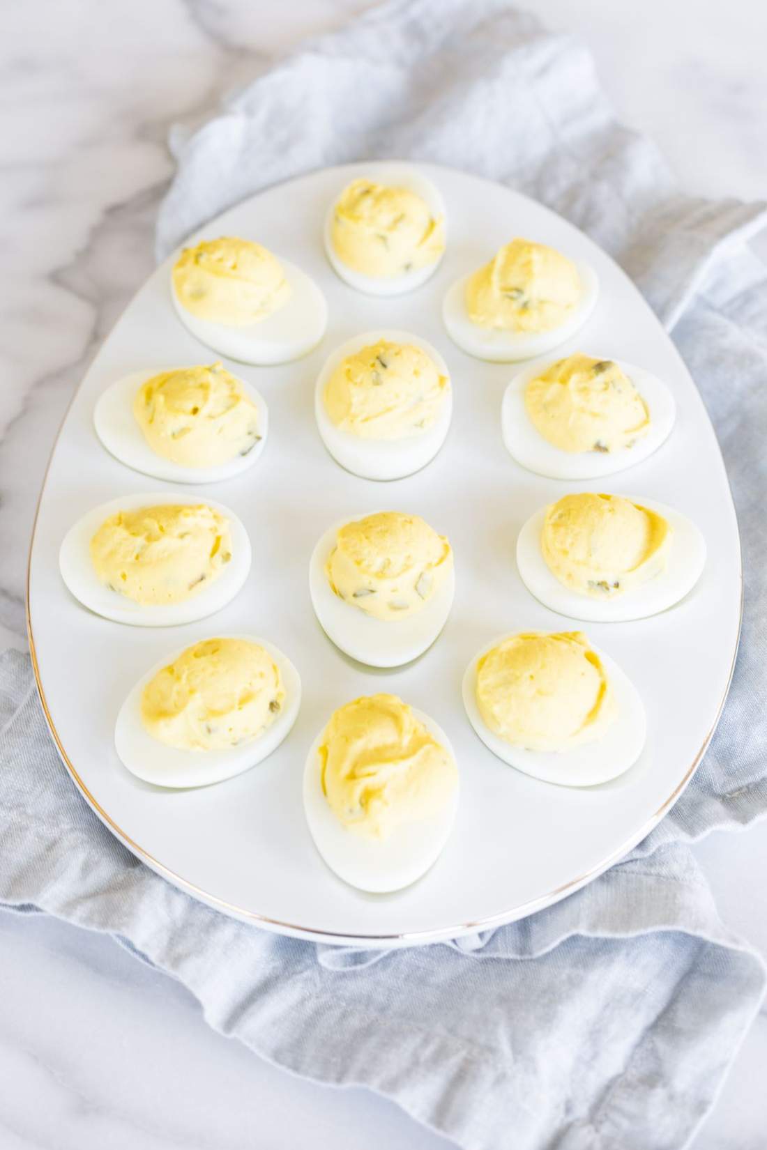 Classic deviled eggs with creamy yolk filling, smoky paprika, fresh chives, and crunchy bacon bits