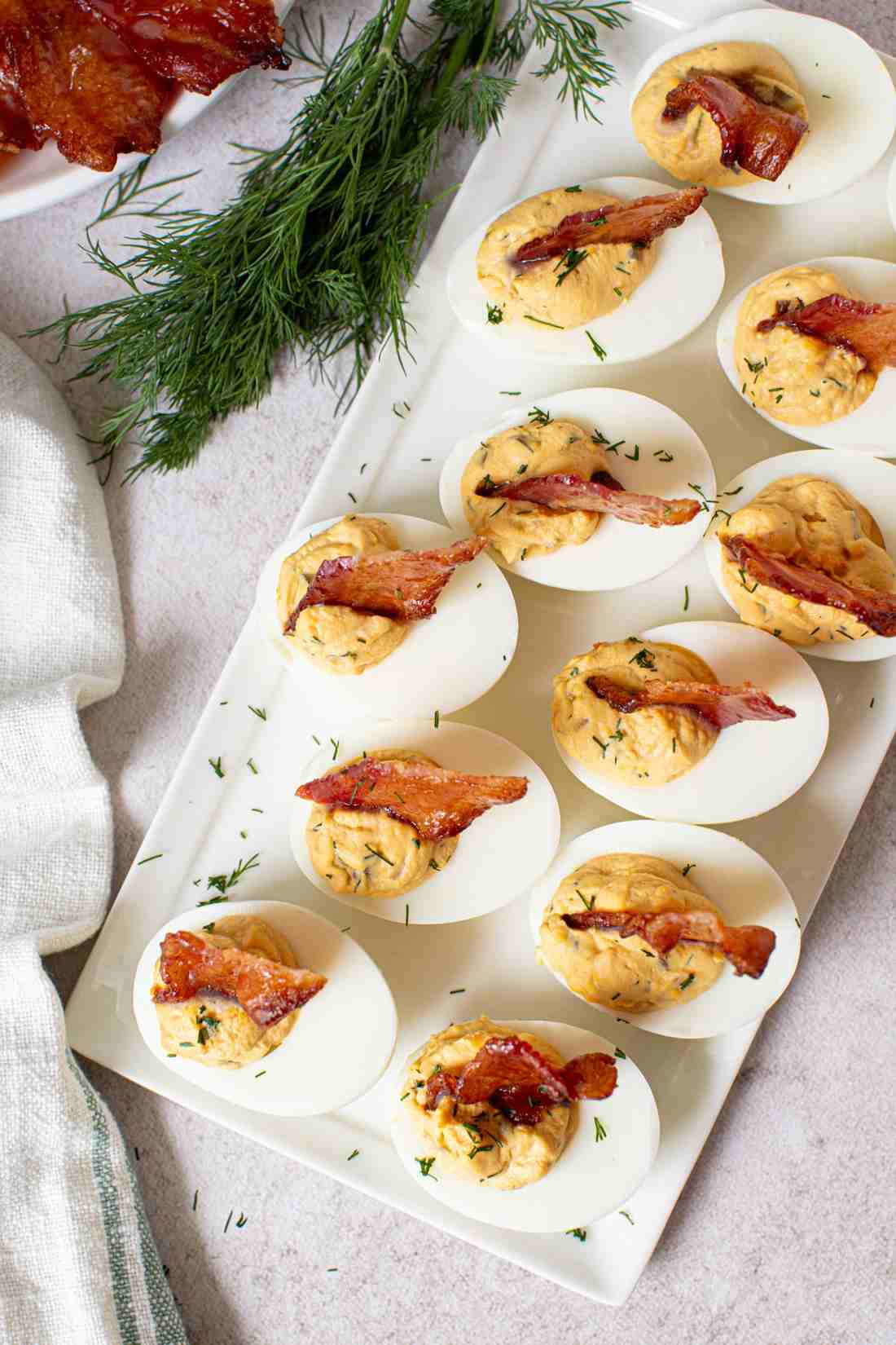 Classic deviled eggs with creamy yolk filling, smoky paprika, fresh chives, and crunchy bacon bits