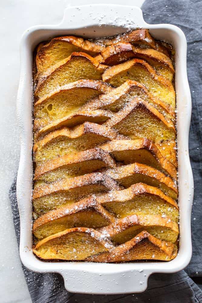 Golden French toast casserole topped with glossy maple syrup and toasted pecans