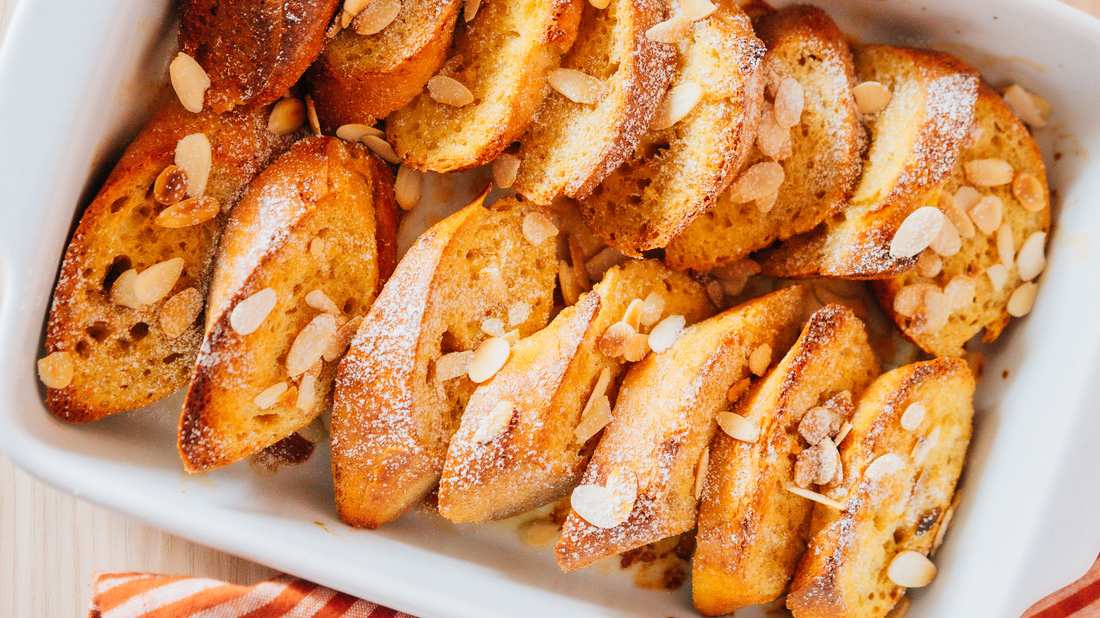Classic French toast casserole with golden custardy bread cubes, warm berries, and maple syrup drizzle