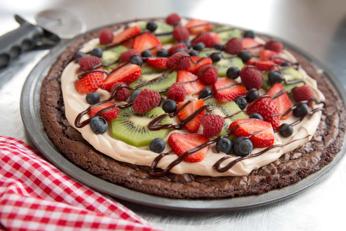 Chocolate brownie fruit pizza with cream cheese frosting, pineapple, kiwi, and mango slices