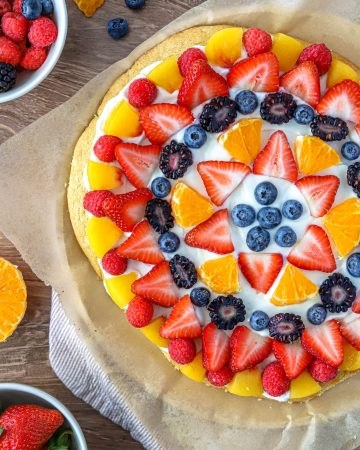 Sugar cookie fruit pizza with cream cheese frosting, fresh blueberries, lemon zest, and kiwi slices