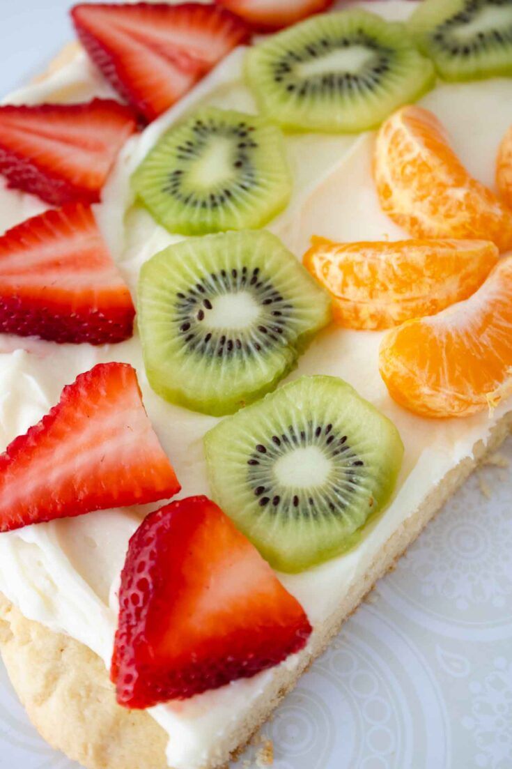 Sugar cookie fruit pizza topped with cream cheese frosting, grapefruit segments, strawberries, and blueberries
