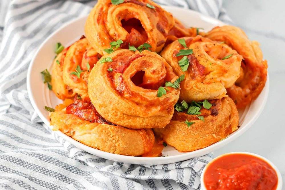 Sugar cookie dough rolled with cream cheese frosting and colorful fruit strips, sliced into pinwheel bites, fun fruit pizza roll‑ups