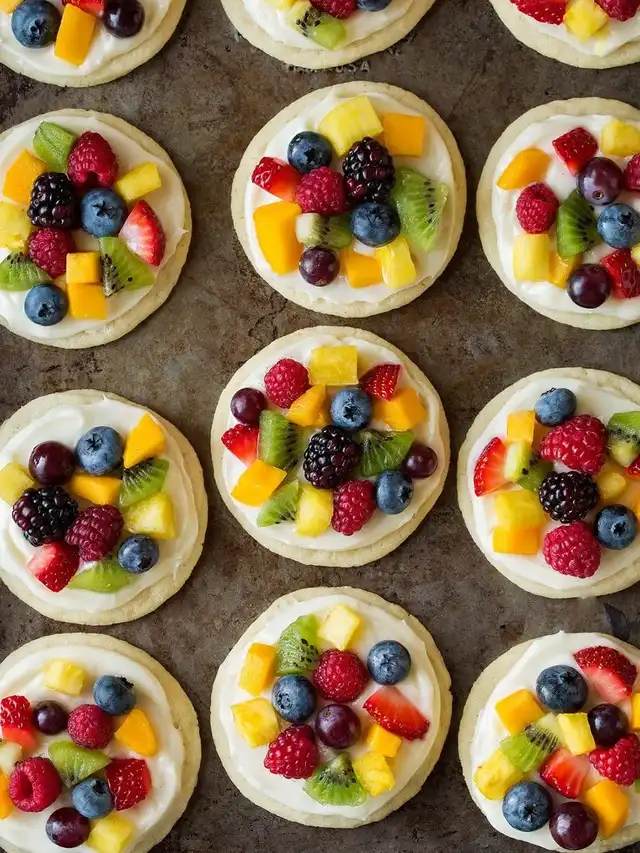 Sugar cookie crust with lemon‑cream cheese frosting, sliced lemon, blueberries, and a glossy lemon glaze, bright fruit pizza