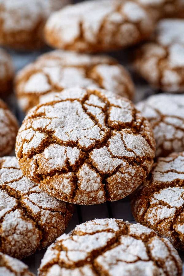 Crinkled gingerbread cookies dusted with powdered sugar, warm spices, festive texture