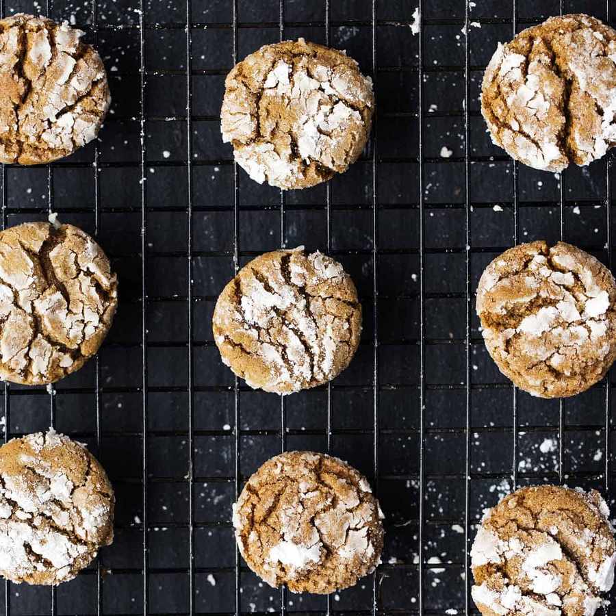 Gingerbread crinkle cookies cooled on dark rack, warm spices, crisp texture, holiday vibe
