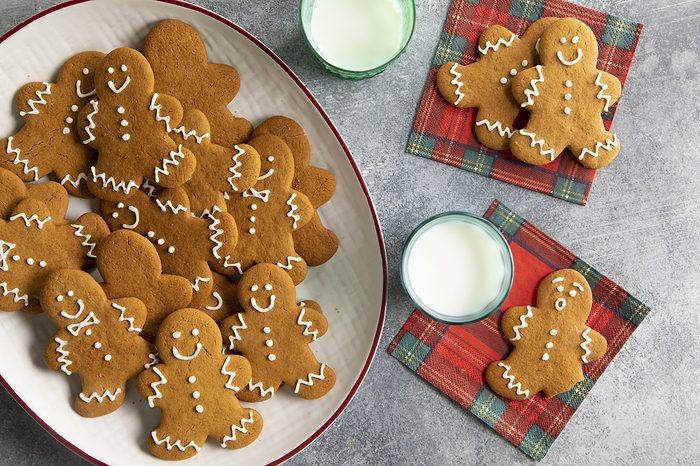 Decorated gingerbread men cookies with festive icing, presented with a glass of milk for Santa