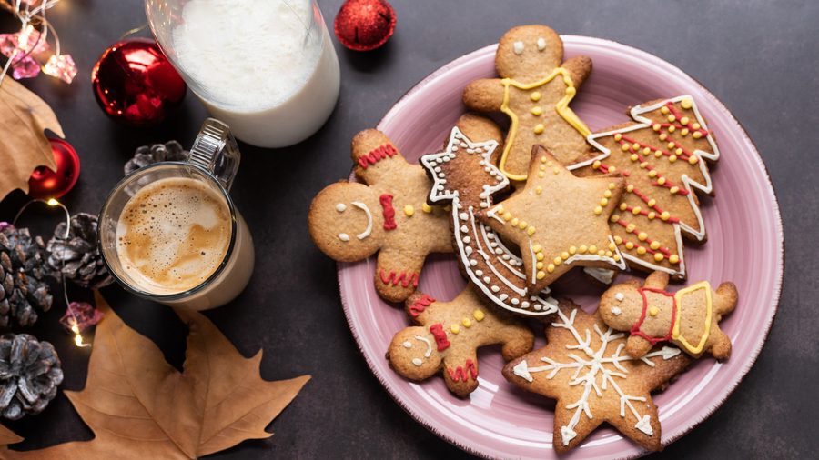 Decorated gingerbread cookies with swirls of icing, served alongside steaming hot cocoa
