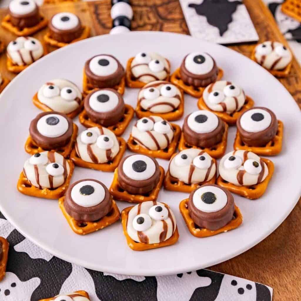 Square pretzels topped with melted caramel Rolo candies, pecan halves or pretzel legs, and candy eyes.