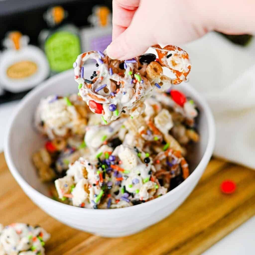 Festive autumn party Chex mix with glazed caramel popcorn, candy corn, salted almonds, and pretzels.