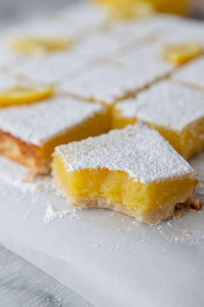 Bright lemon bars featuring a golden shortbread base, lemon curd, and powdered sugar topping