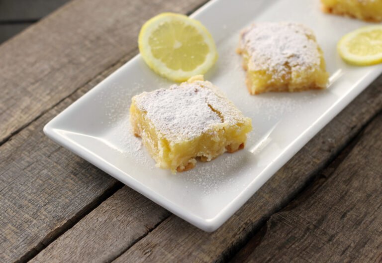 Bright lemon bars on a golden gluten‑free shortbread crust, dusted with powdered sugar