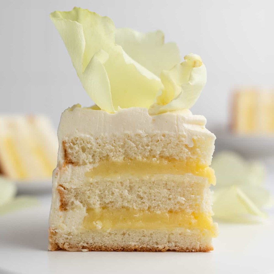 Light lemon sponge cake layered with lemon curd and fluffy whipped cream, bright citrus, garnished with berries